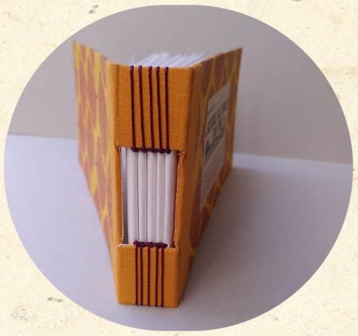 Tranche d'un carnet relié en reliure Buttonhole avec couture apparente en fil orange - Cosette Cartonera