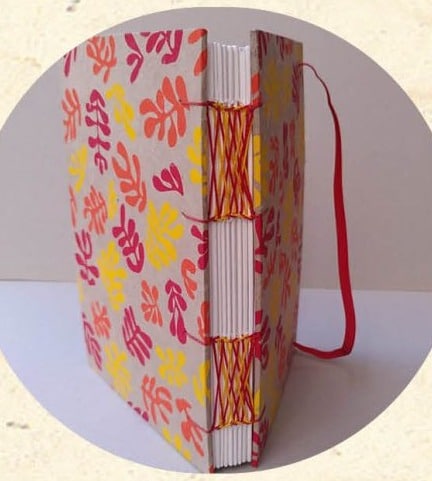 Tranche d'un carnet relié en reliure Celte avec couture apparente à croisements de fils rouge et jaune - Cosette Cartonera