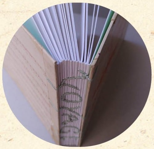 Tranche d'un carnet relié en reliure Copte à dos écrit montrant l'assemblage des cahiers - Cosette Cartonera